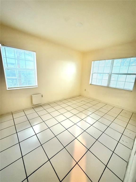 An empty room features white tiled floors, two windows with blinds, and a wall-mounted heater — 1931 7TH STREET S, ST PETERSBURG, FL