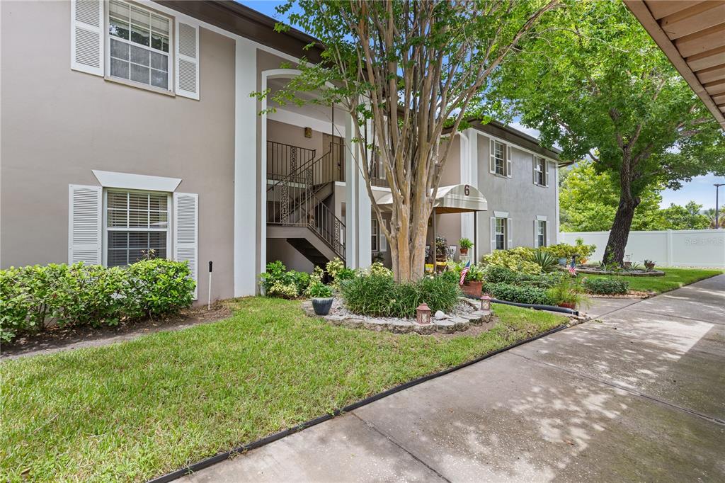 A two-story apartment building exterior features a central staircase, landscaping, and a paved walkway — 5265 E BAY DRIVE UNIT 612, CLEARWATER, FL