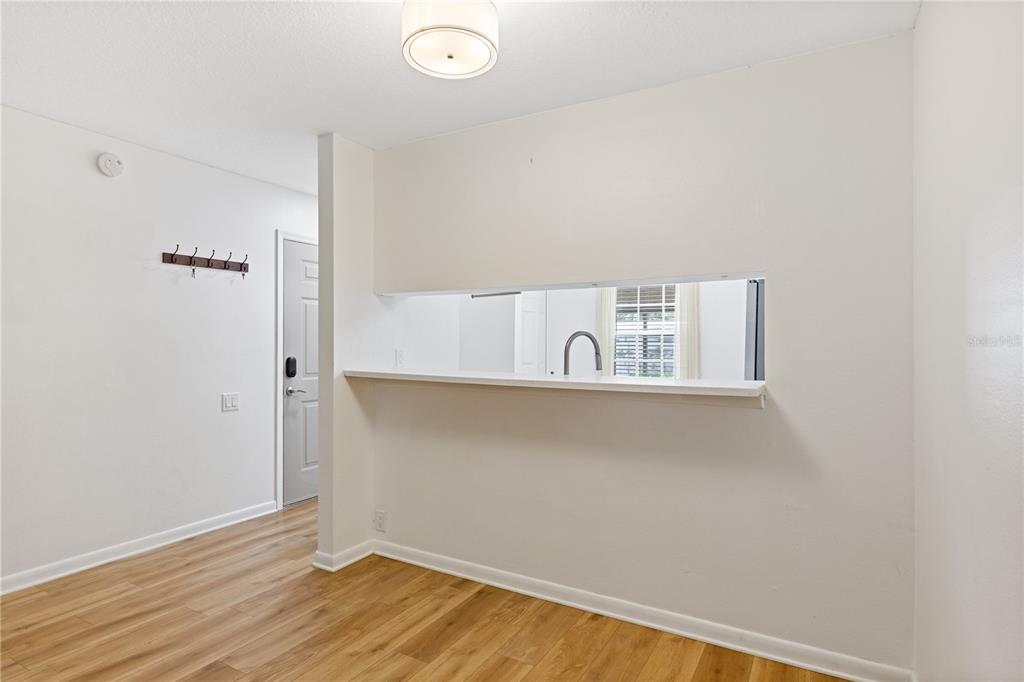 A view of a dining area featuring light wood flooring, a pass-through window, and a doorway — 5265 E BAY DRIVE UNIT 612, CLEARWATER, FL