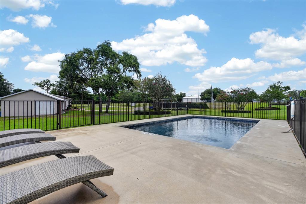 A rectangular swimming pool sits on a concrete patio next to several lounge chairs — 350 FOX HOLLOW FARMS ROAD, PIERSON, FL