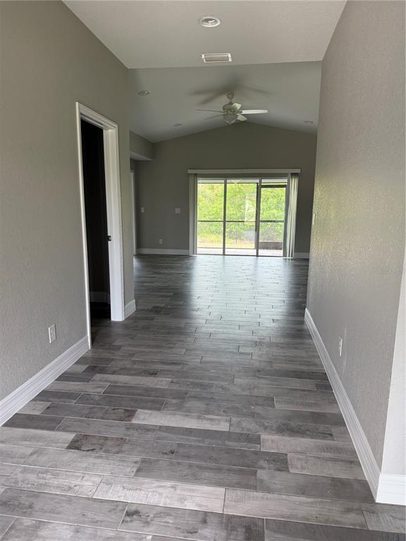 A hallway with wood-look tile flooring, light gray walls, and a glass-paneled exterior door — 315 SWEETWATER DRIVE, ROTONDA WEST, FL