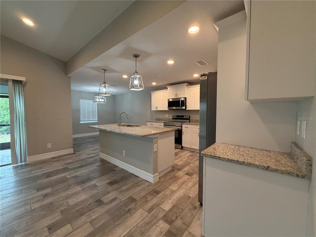 A bathroom features a granite vanity, white cabinets, and a tub-shower with wood-look tile walls — 315 SWEETWATER DRIVE, ROTONDA WEST, FL