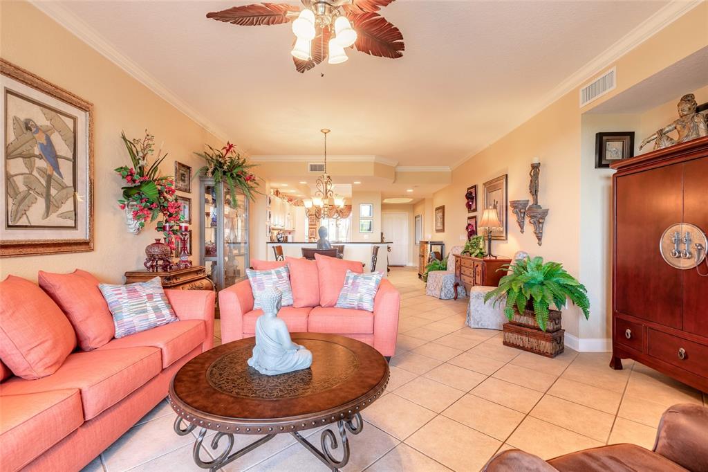 A living room features coral sofas, a round metal coffee table, and tile flooring — 263 MINORCA BEACH WAY UNIT 304, NEW SMYRNA BEACH, FL