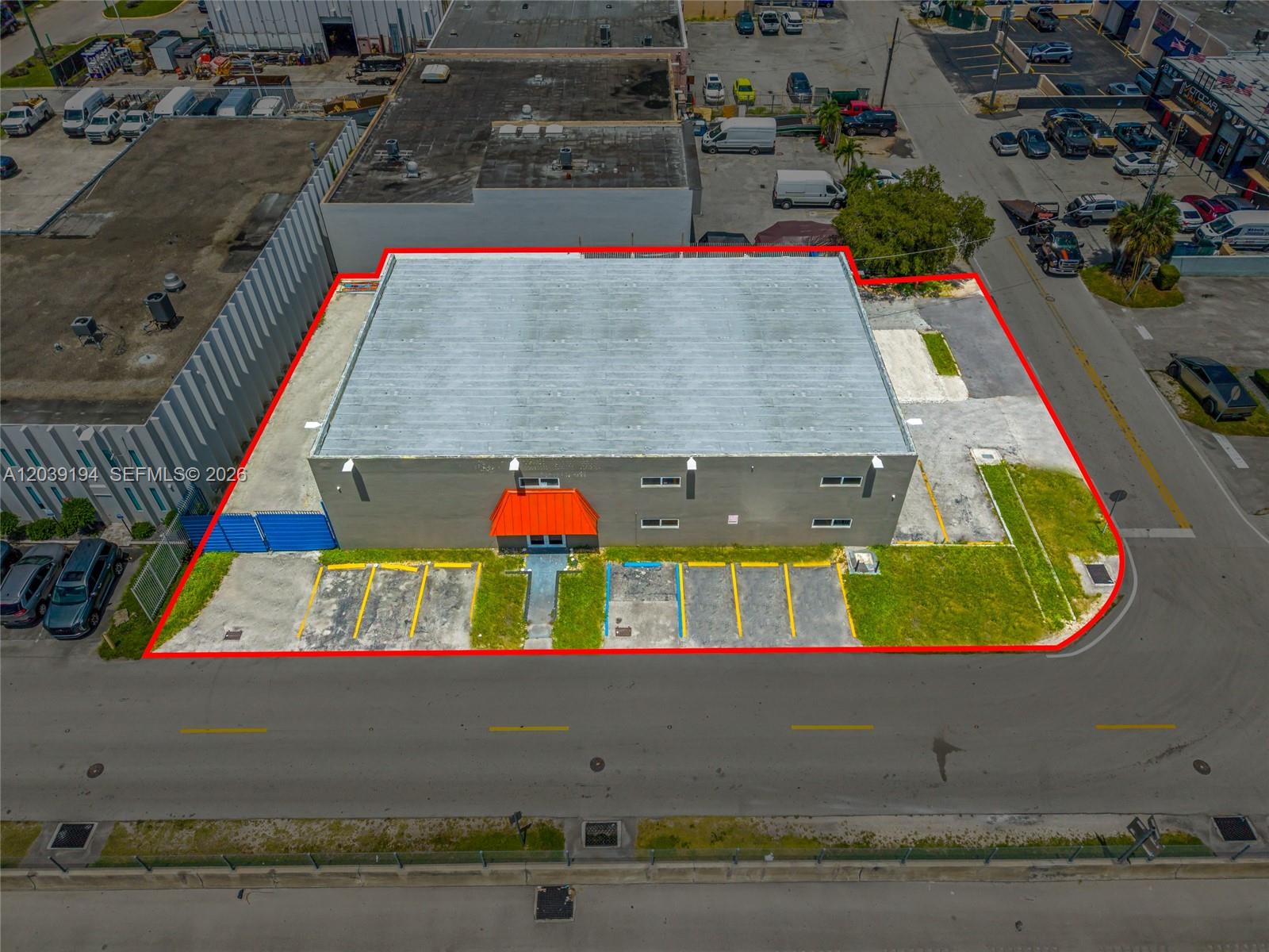 An aerial view shows a commercial building with a gray roof and orange entrance awning — 5280 NW 77th Ct, Doral FL 33166, DORAL, FL