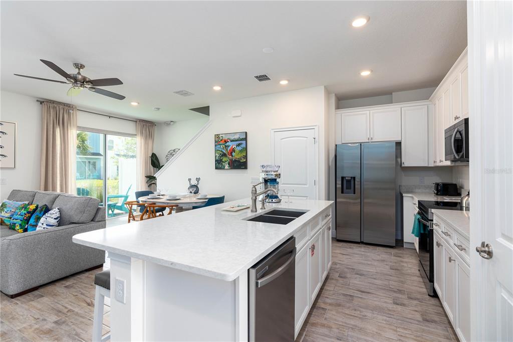 A kitchen with a white island and stainless steel appliances opens into a living area — 2960 ON THE ROCKS POINT, KISSIMMEE, FL