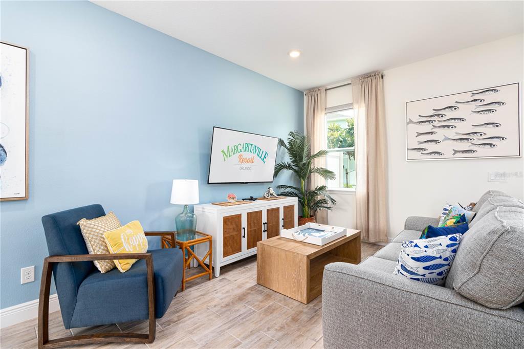 A living room features a blue accent wall, a gray sofa, and a television console — 2960 ON THE ROCKS POINT, KISSIMMEE, FL