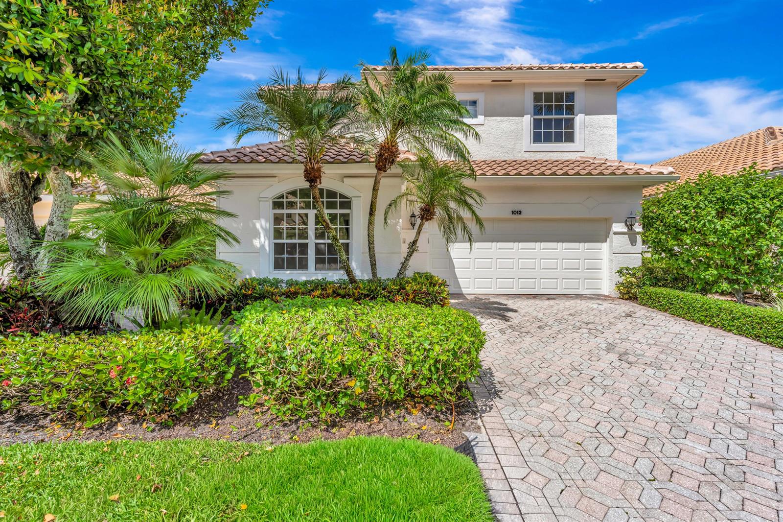 A two-story stucco house with a tiled roof, palm trees, and a paved driveway — 1012 Diamond Head Way, Palm Beach Gardens FL 33418, PALM BEACH GARDENS, FL