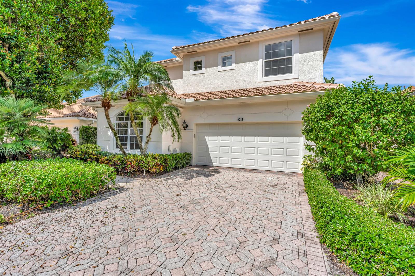A two-story stucco house features a tiled roof, a paved driveway, and a two-car garage — 1012 Diamond Head Way, Palm Beach Gardens FL 33418, PALM BEACH GARDENS, FL