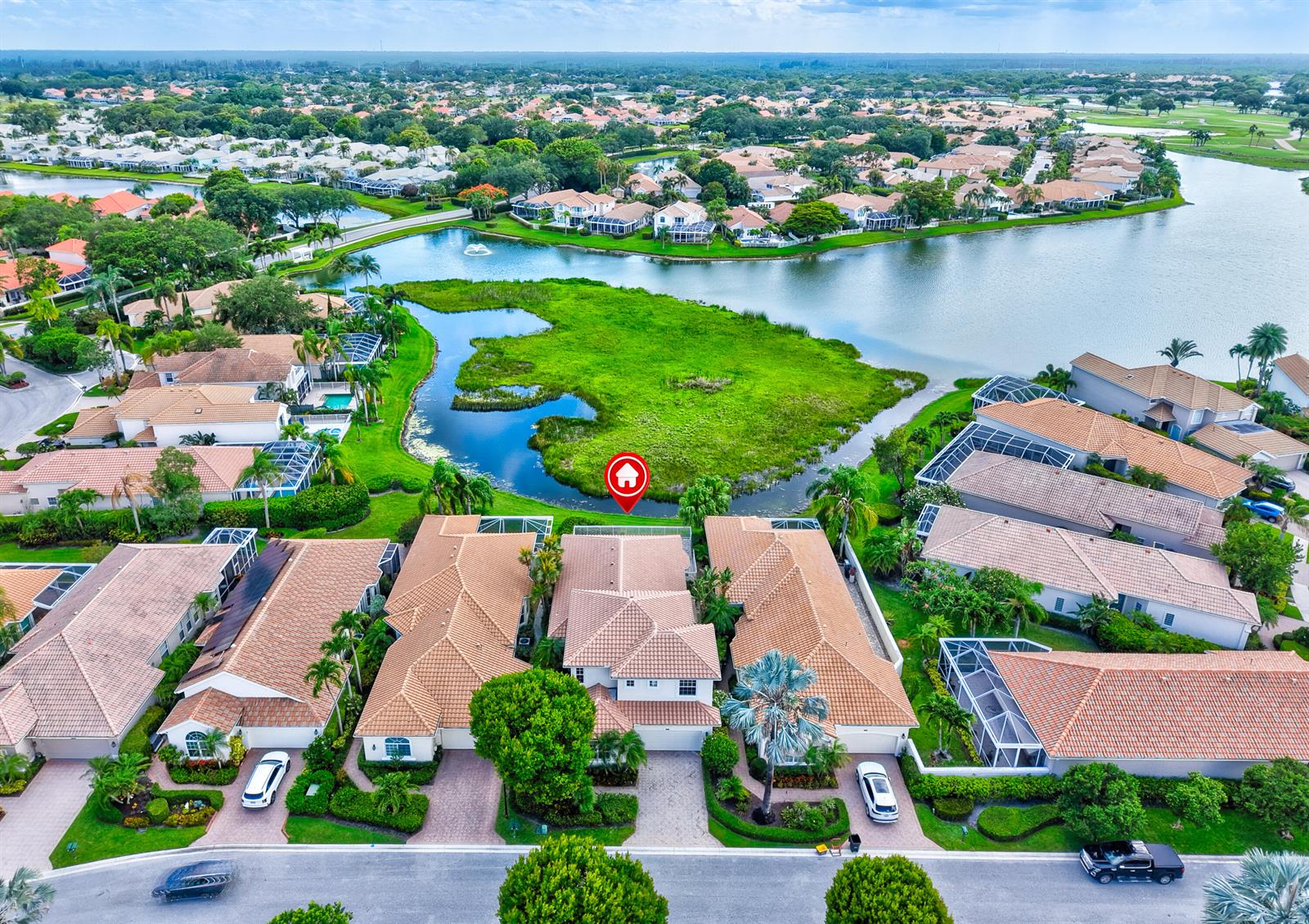An aerial view shows a residential house with a tiled roof situated near a lake — 1012 Diamond Head Way, Palm Beach Gardens FL 33418, PALM BEACH GARDENS, FL