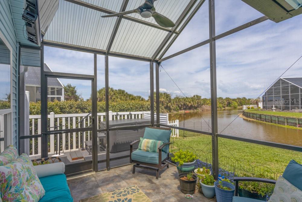 A screened-in patio features tile flooring, a ceiling fan, and views of a canal — 33 BEDFORD DRIVE, PALM COAST, FL