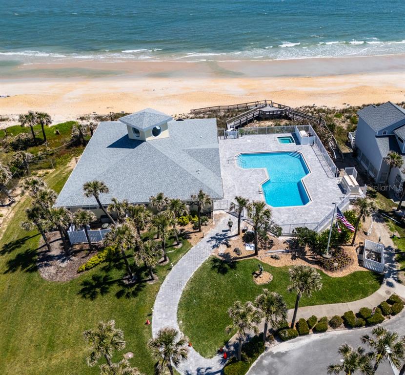 An aerial view shows a beachside building with a pool, patio, and surrounding palm trees — 33 BEDFORD DRIVE, PALM COAST, FL