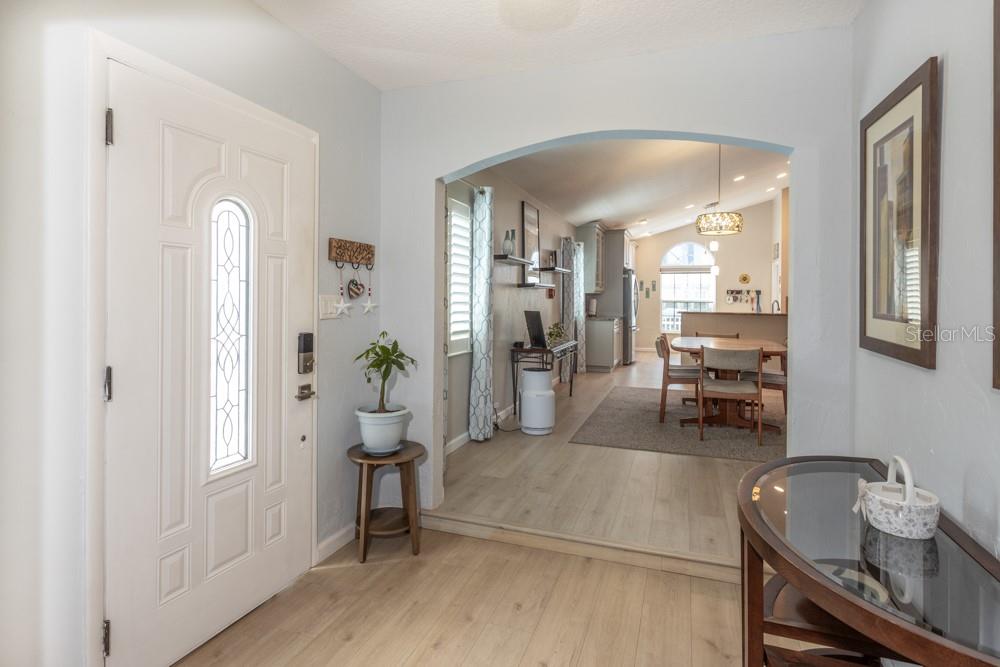 An entryway with light wood flooring leads through an arched opening into a dining area — 33 BEDFORD DRIVE, PALM COAST, FL