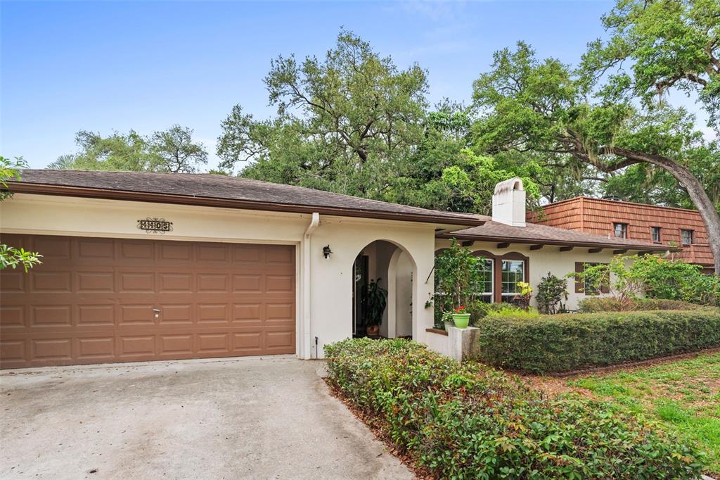 A house exterior features a brick patio, a small fountain, and a metal bench — 4405 W MELROSE AVENUE, TAMPA, FL