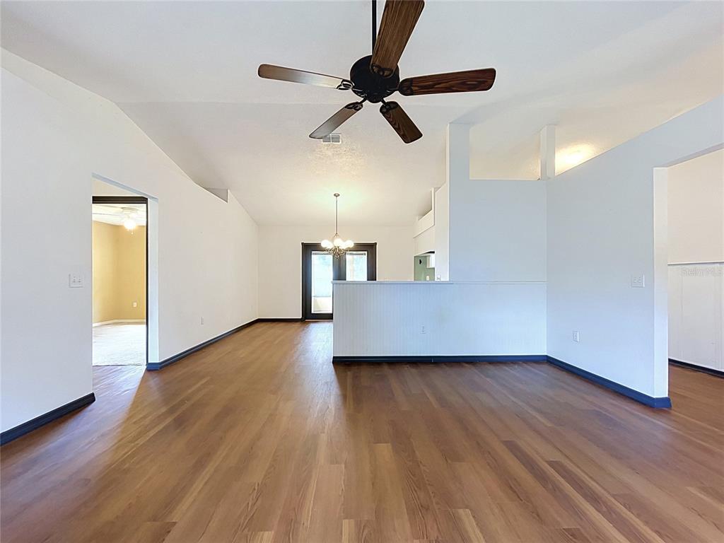 An open-concept living area features wood-look flooring, a ceiling fan, and a partial wall — 3974 LIME TREE LANE, LAKELAND, FL