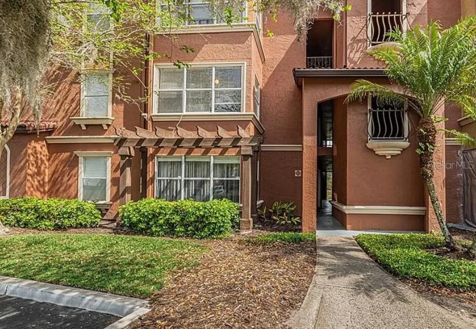 A multi-story brown stucco apartment building with a wooden pergola and a palm tree — 5140 CONROY ROAD UNIT 27, ORLANDO, FL