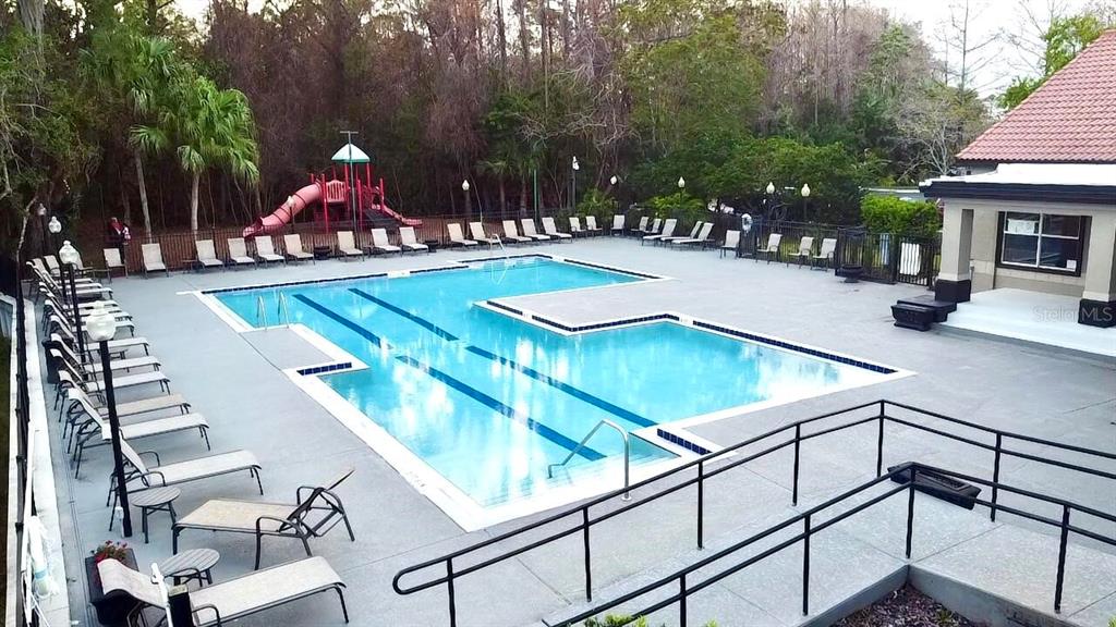 An outdoor swimming pool with lounge chairs and a playground sits beside a building — 5140 CONROY ROAD UNIT 27, ORLANDO, FL