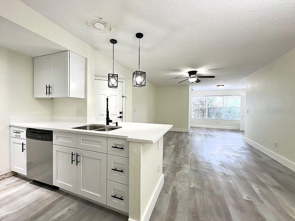 A kitchen with white cabinets and a peninsula overlooks an open-concept living area — 5140 CONROY ROAD UNIT 27, ORLANDO, FL