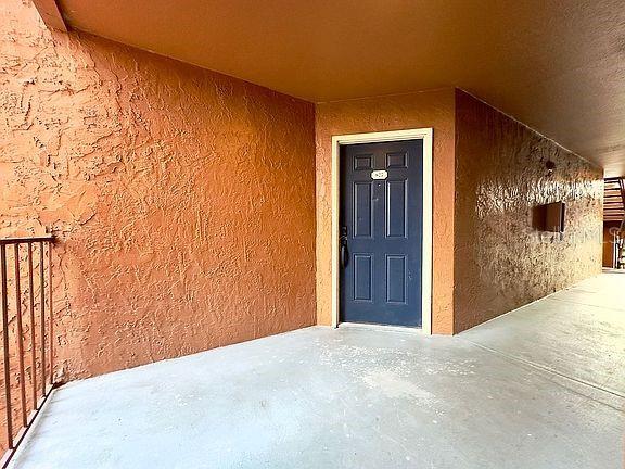 A dark blue front door is set into a textured, orange-painted exterior wall — 5140 CONROY ROAD UNIT 27, ORLANDO, FL