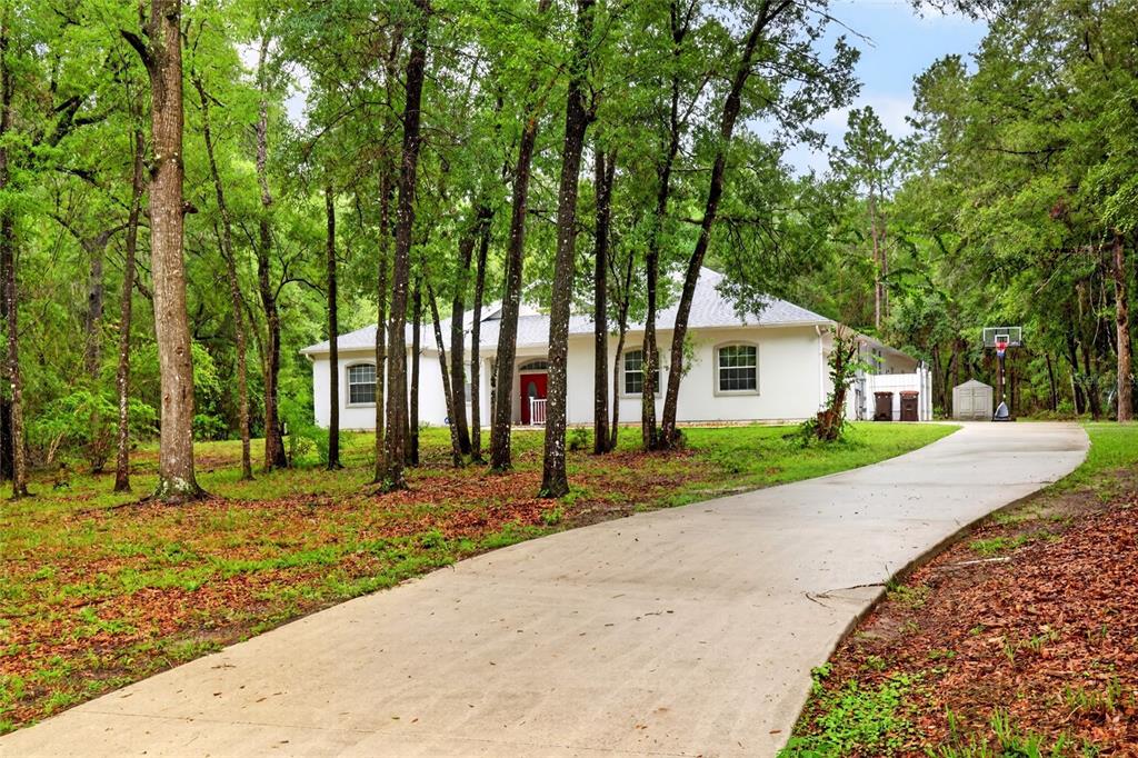 A white house with a red front door sits at the end of a concrete driveway — 7550 SW 185TH CIRCLE, DUNNELLON, FL