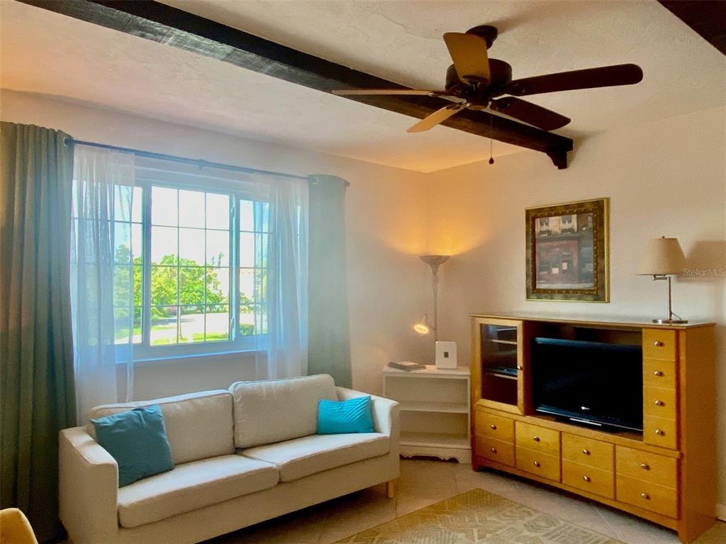 A living room features a beige sofa, wooden media console, ceiling fan, and exposed beams — 238 TAMPA AVENUE W UNIT 6B, VENICE, FL