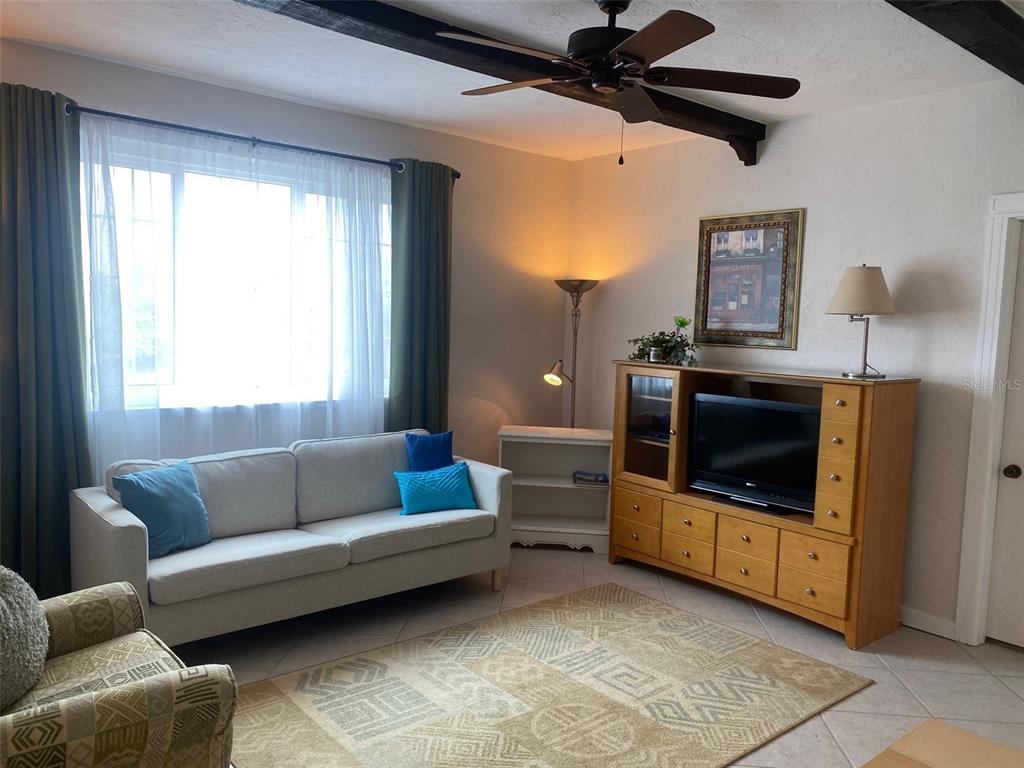A living room features a light-colored sofa, wooden entertainment center, ceiling fan, and area rug — 238 TAMPA AVENUE W UNIT 6B, VENICE, FL
