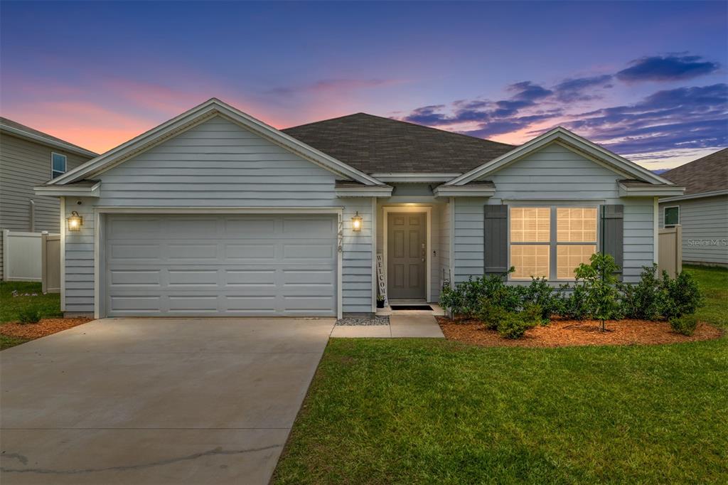 A single-story house with light blue siding, a two-car garage, and a front lawn — 17478 NW 172ND AVENUE, ALACHUA, FL