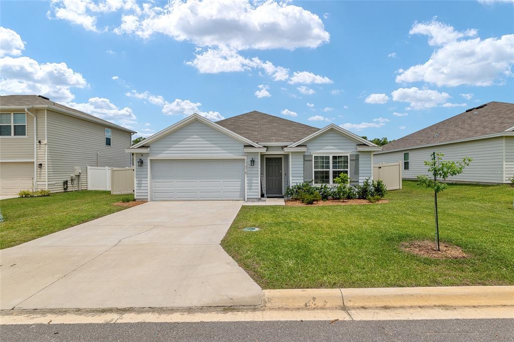 A light blue single-story house with a two-car garage and a concrete driveway — 17478 NW 172ND AVENUE, ALACHUA, FL