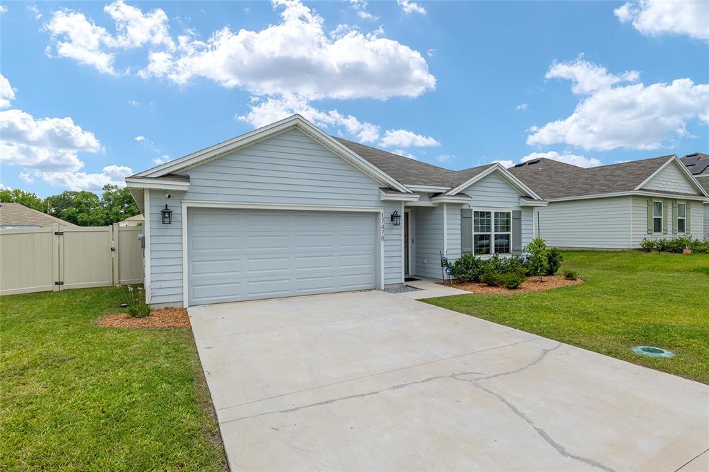 A light blue single-story house features a two-car garage and a concrete driveway — 17478 NW 172ND AVENUE, ALACHUA, FL