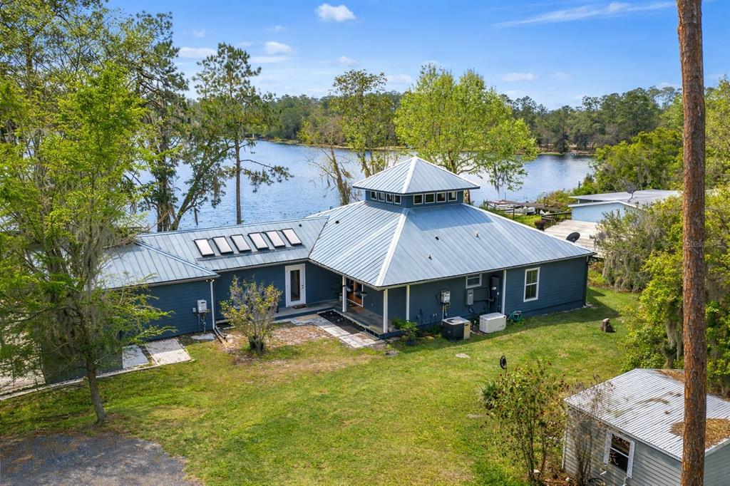 An aerial view of a blue house with a metal roof and cupola near a lake — 299 RILEY LAKE DRIVE, HAWTHORNE, FL