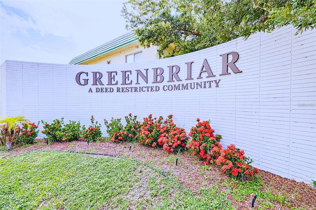 A curved white brick wall displays the Greenbriar community name behind a bed of flowers — 2003 GREENBRIAR BOULEVARD UNIT 4, CLEARWATER, FL