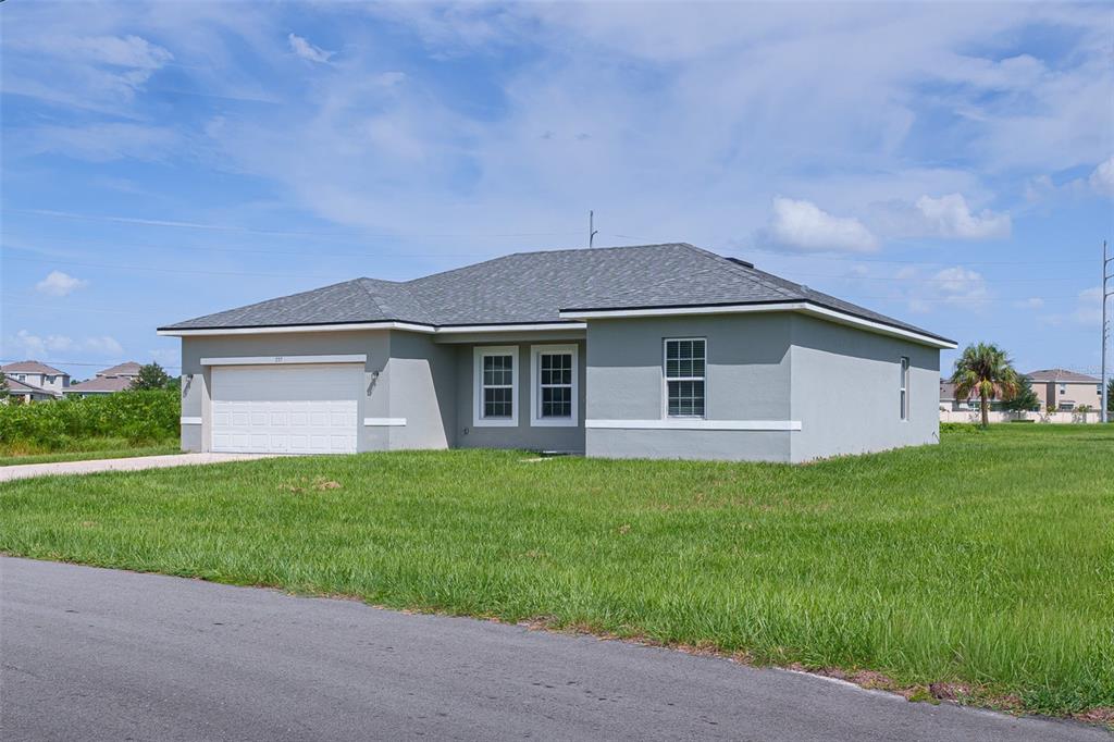 A single-story gray house with a two-car garage sits on a grassy lot — 237 CIMARRON DRIVE, POINCIANA, FL