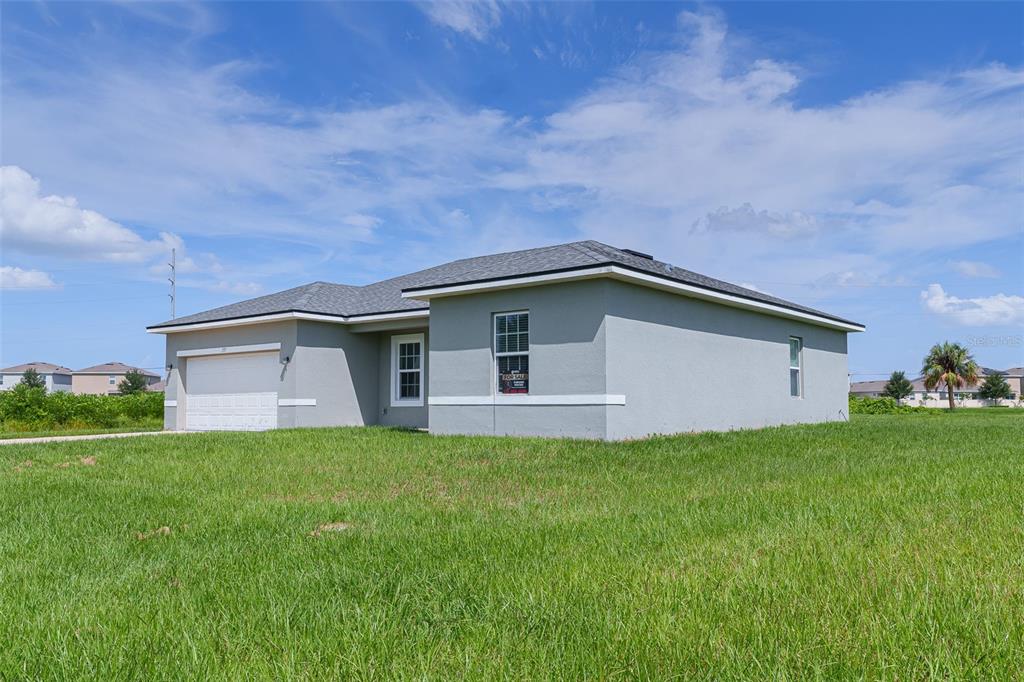 A single-story house with a gray stucco exterior, a two-car garage, and a grassy yard — 237 CIMARRON DRIVE, POINCIANA, FL