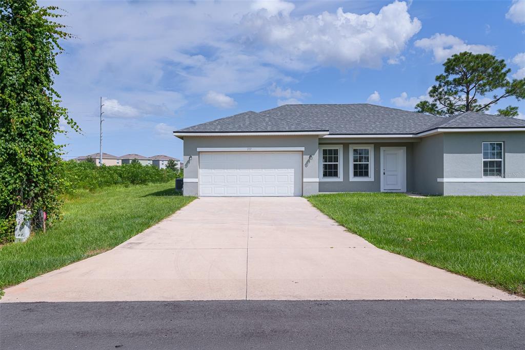 A single-story house with a white garage door, gray siding, and a concrete driveway — 237 CIMARRON DRIVE, POINCIANA, FL