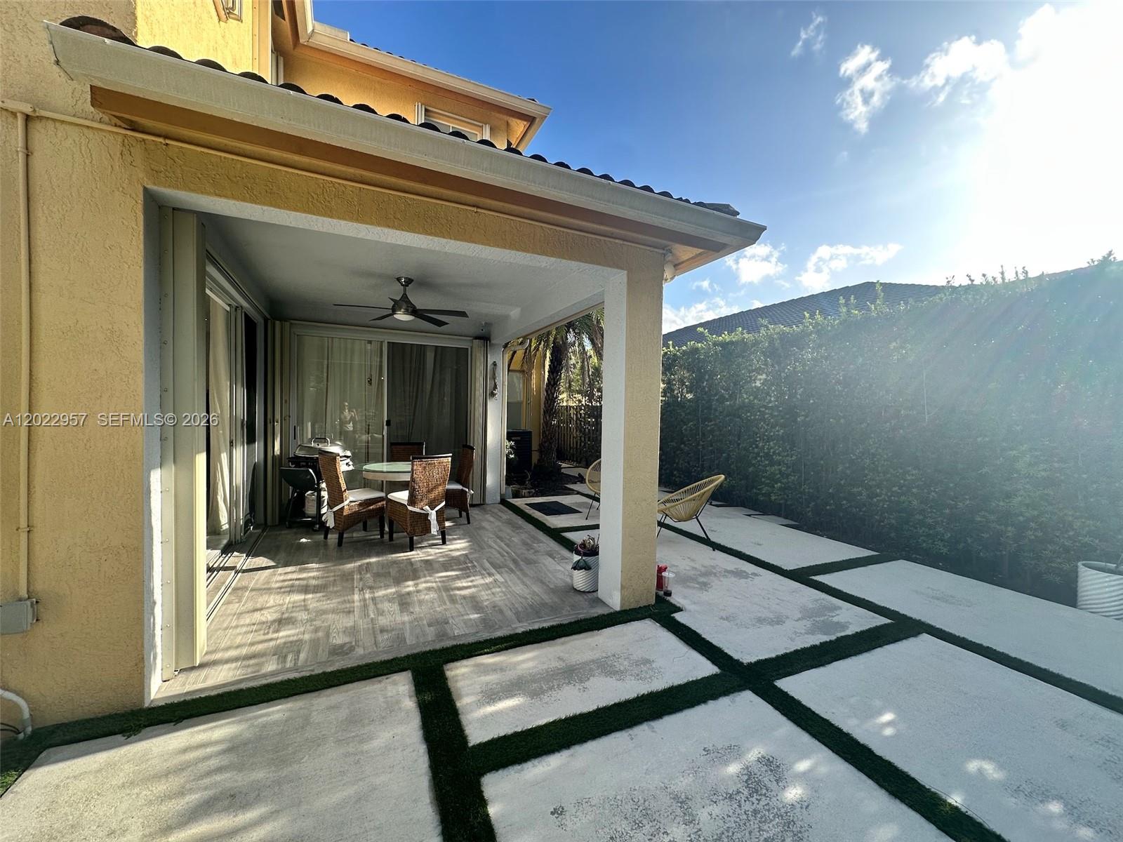 A covered patio features wood-look tile flooring, a ceiling fan, and an adjacent paved courtyard — 10919 NW 80th Ln, Doral FL 33178, DORAL, FL
