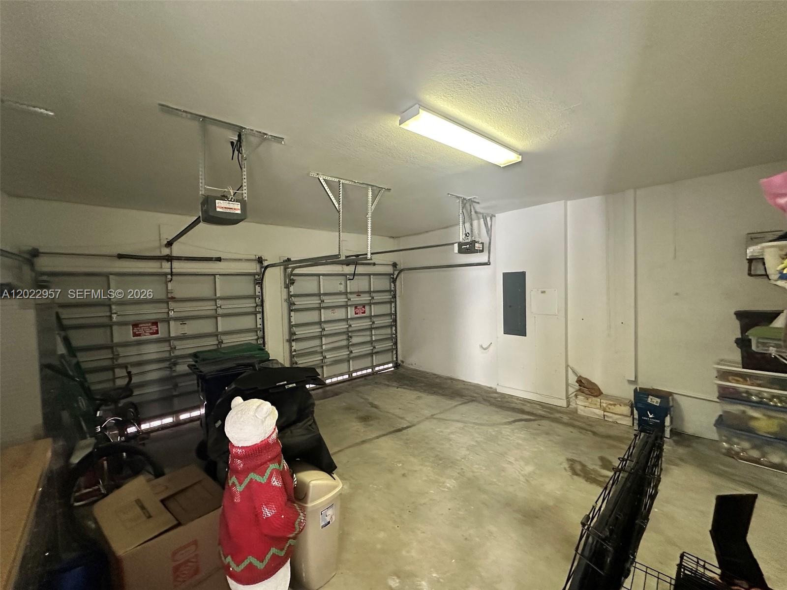 This two-car garage features concrete floors, white walls, and two overhead garage door openers — 10919 NW 80th Ln, Doral FL 33178, DORAL, FL