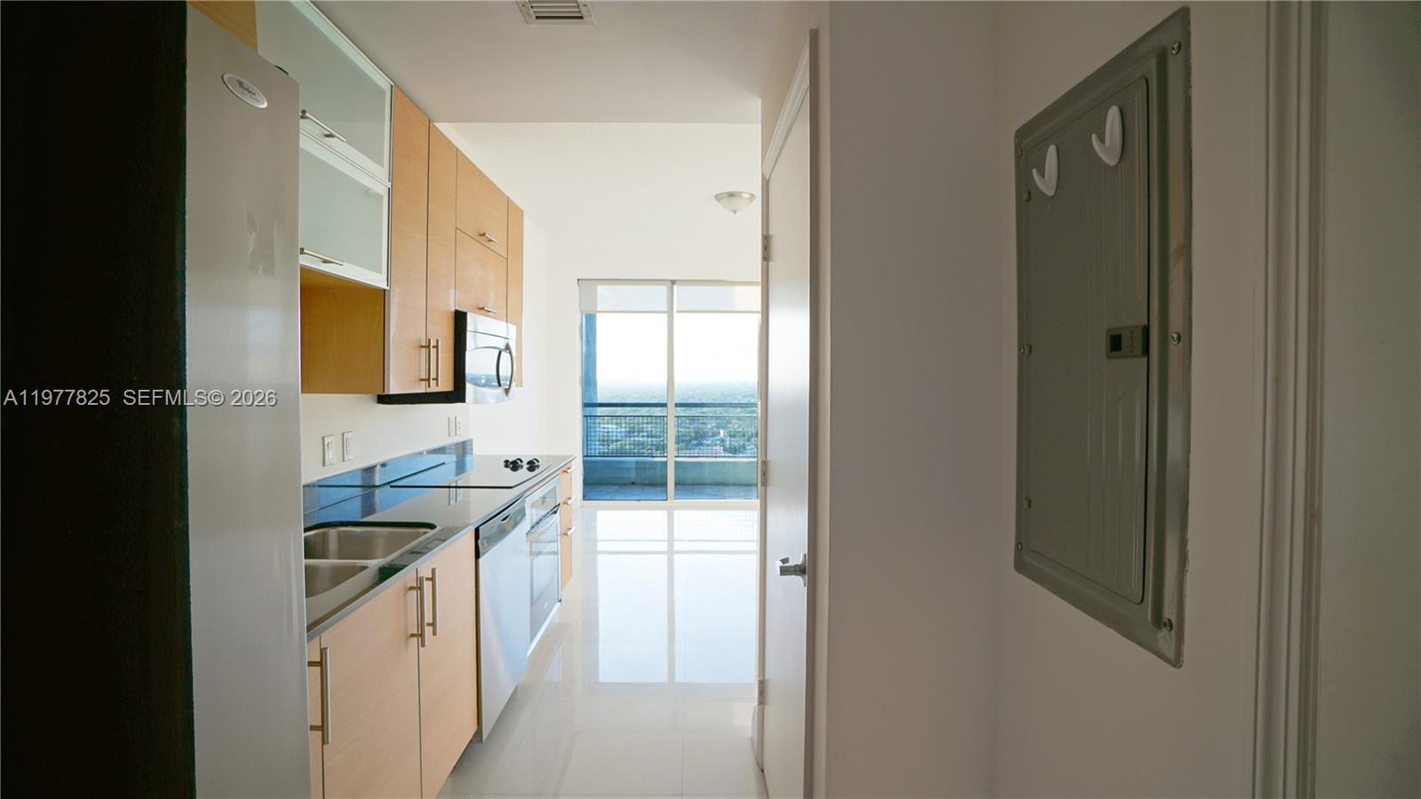 A galley kitchen features light wood cabinets, stainless steel appliances, and a balcony view — 60 SW 13th St # 2215, Miami FL 33130, MIAMI, FL