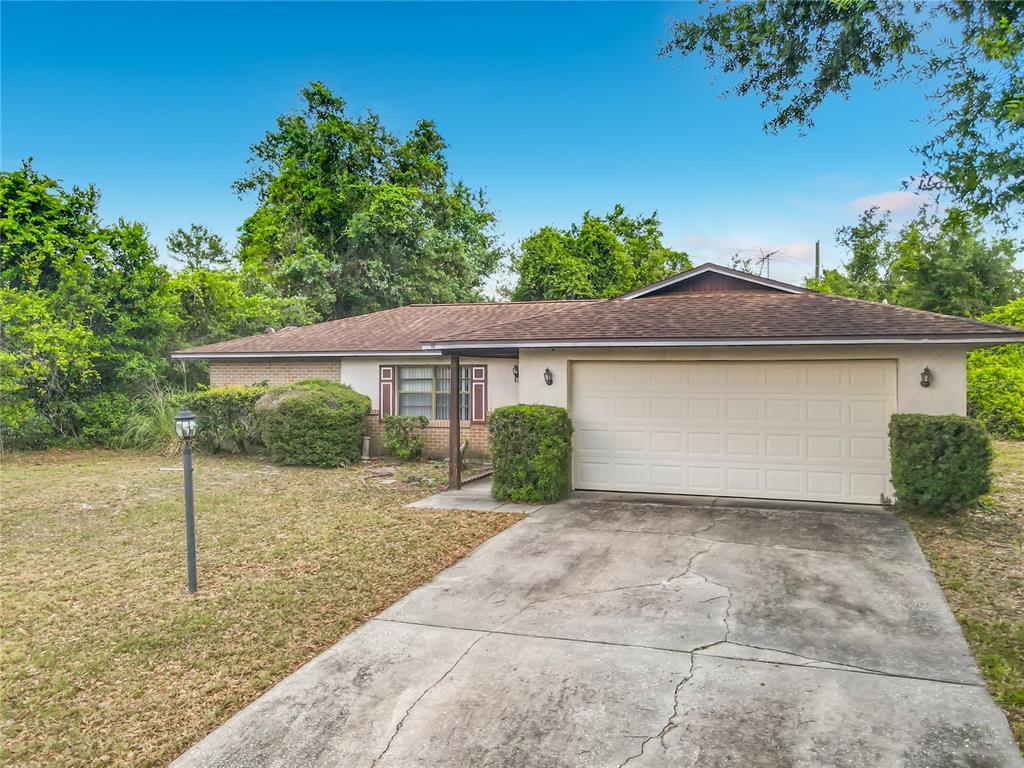A single-story house with a beige exterior, a two-car garage, and a concrete driveway — 625 BRUNSWICK TERRACE, DELTONA, FL