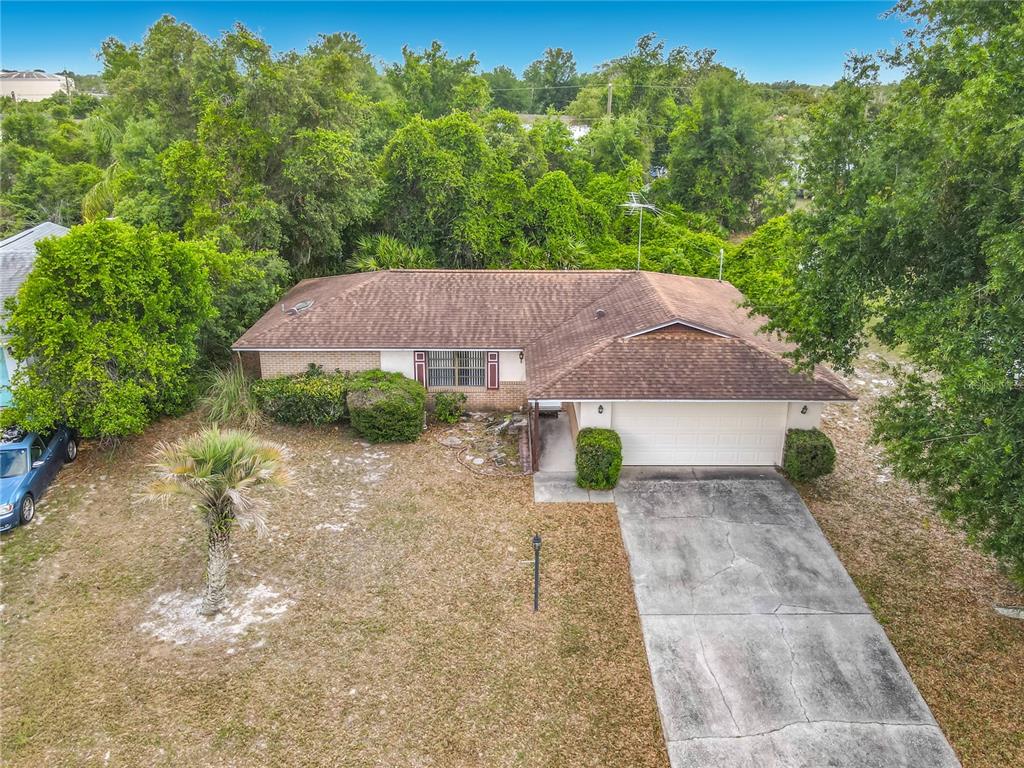 An aerial view shows a single-story house with a brown roof and a concrete driveway — 625 BRUNSWICK TERRACE, DELTONA, FL
