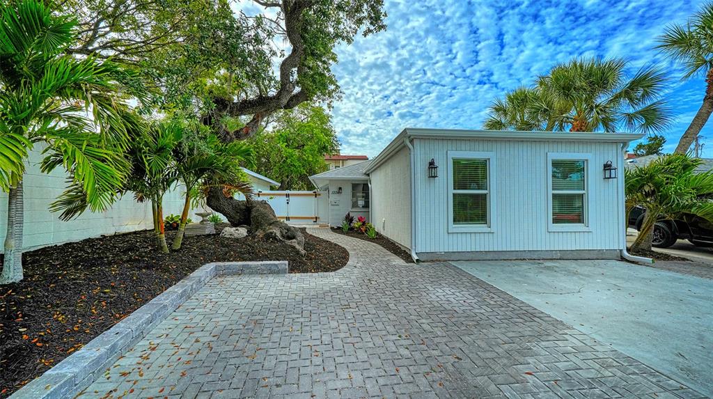 A white house with a paved driveway and walkway sits beside a large, mature tree — 1224 MOONMIST CIRCLE UNIT S-3, SARASOTA, FL