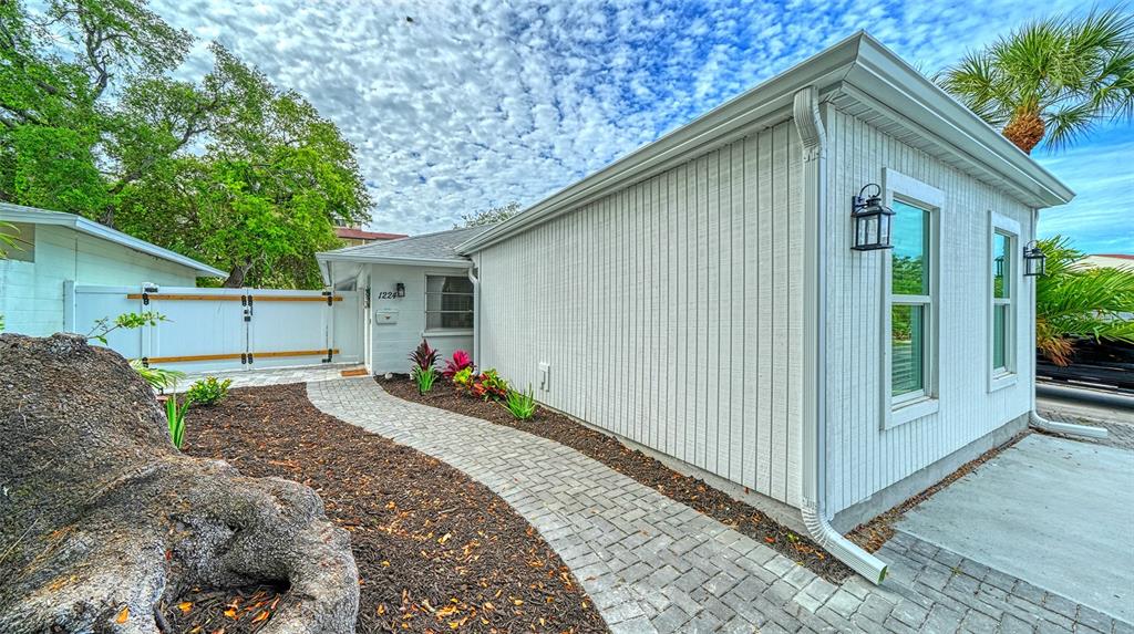 A white house exterior features a paved walkway leading to the front door and gate — 1224 MOONMIST CIRCLE UNIT S-3, SARASOTA, FL