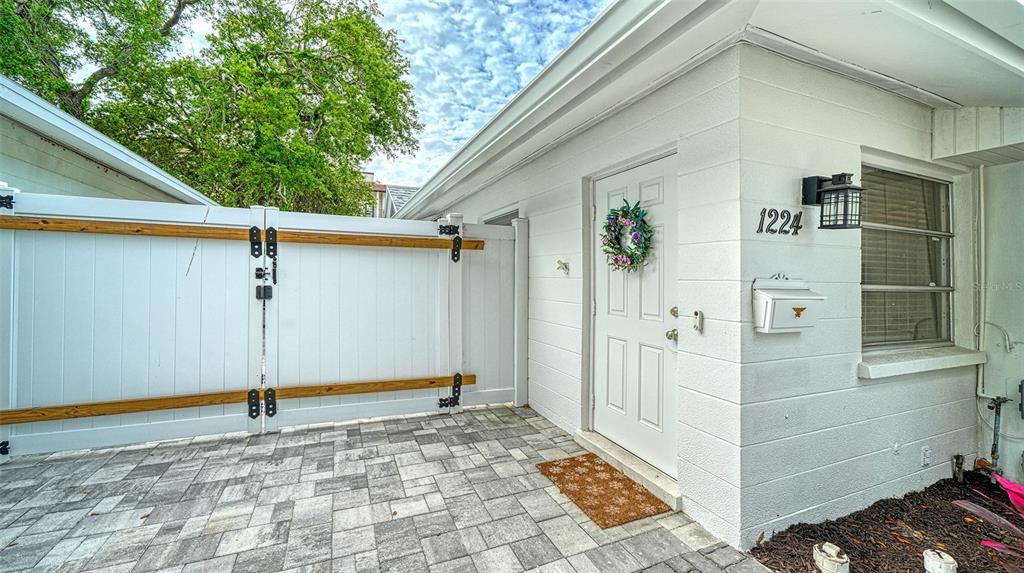 A white exterior wall with a door, house number, mailbox, and a paved patio area — 1224 MOONMIST CIRCLE UNIT S-3, SARASOTA, FL
