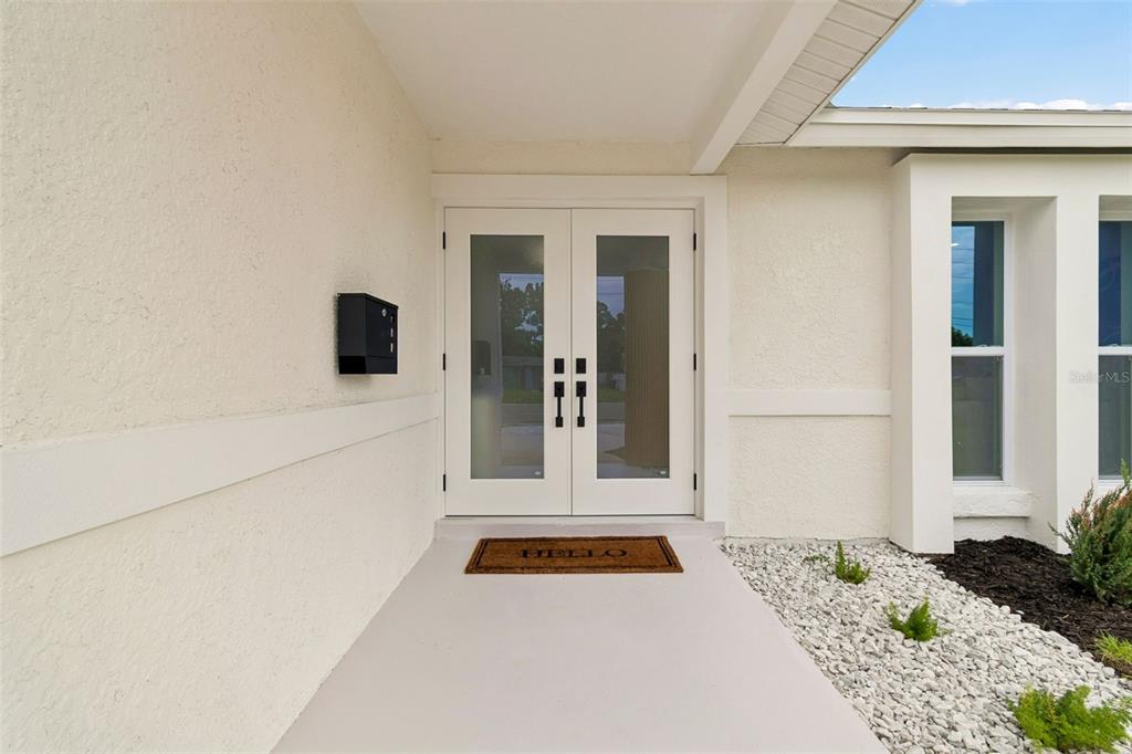 A white double door entrance with glass panels sits under a covered porch — 1137 54TH AVENUE S, ST PETERSBURG, FL