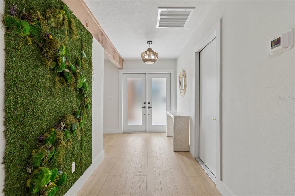 An entryway features light wood flooring, a moss wall, and double glass-paneled front doors — 1137 54TH AVENUE S, ST PETERSBURG, FL