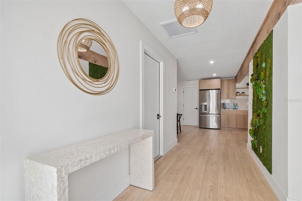 A hallway features a textured console table, a circular gold mirror, and a vertical moss wall — 1137 54TH AVENUE S, ST PETERSBURG, FL