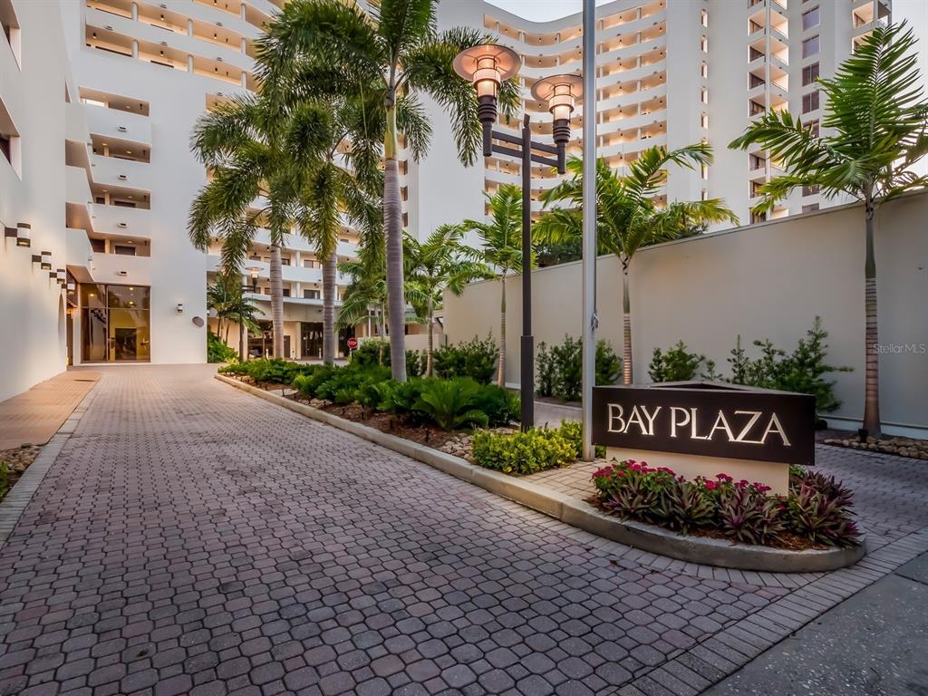A paved driveway leads to the entrance of a white multi-story building named Bay Plaza — 1255 N GULFSTREAM AVENUE UNIT 1106, SARASOTA, FL