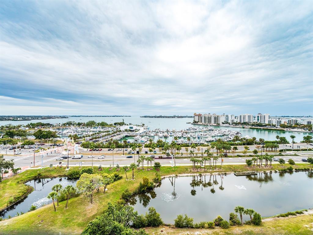 An elevated view shows a marina, a multi-lane road, and a pond with palm trees — 1255 N GULFSTREAM AVENUE UNIT 1106, SARASOTA, FL