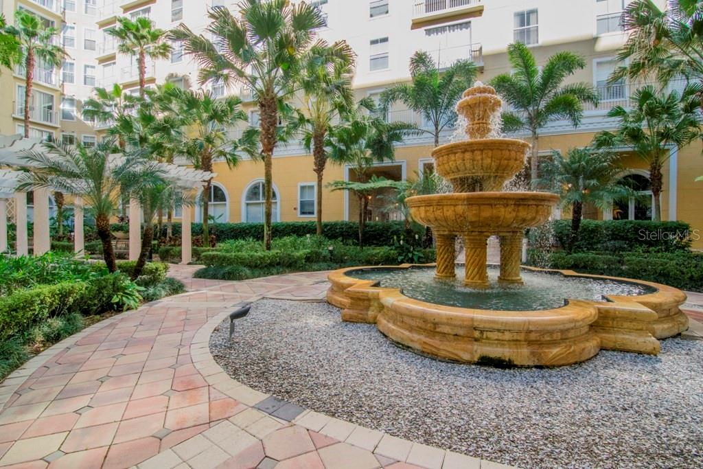 A tiered stone fountain sits in a landscaped courtyard with palm trees and paved walkways — 700 S HARBOUR ISLAND BOULEVARD UNIT 535, TAMPA, FL