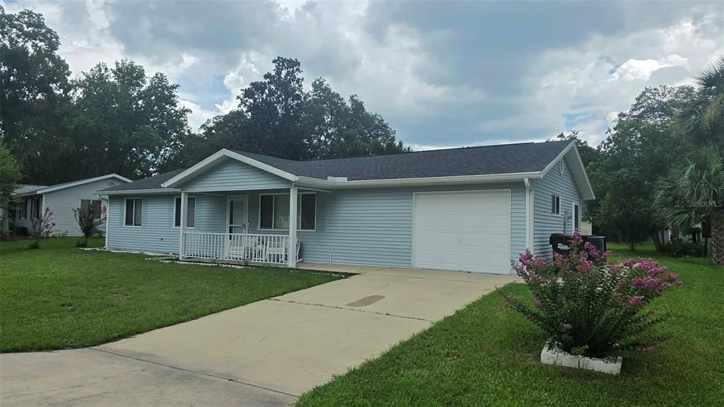 A light blue, single-story house with a front porch, attached garage, and a concrete driveway — 8041 SW 109TH PLACE ROAD, OCALA, FL