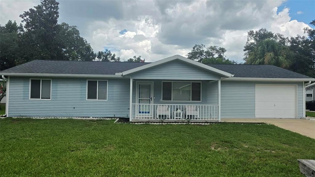A light blue single-story house with a front porch, attached garage, and a grassy lawn — 8041 SW 109TH PLACE ROAD, OCALA, FL
