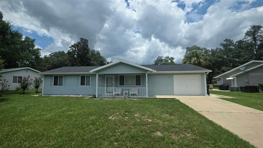 A single-story light blue house with a front porch, attached garage, and a grassy yard — 8041 SW 109TH PLACE ROAD, OCALA, FL